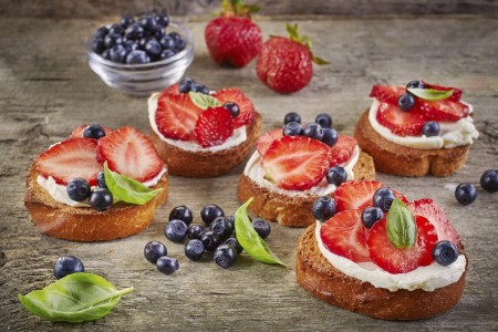 toasted bread with cream cheese and fresh berries on wooden table