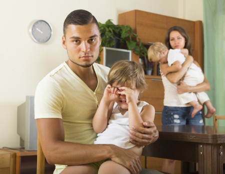 Sad man with young wife and two children having quarrel in home